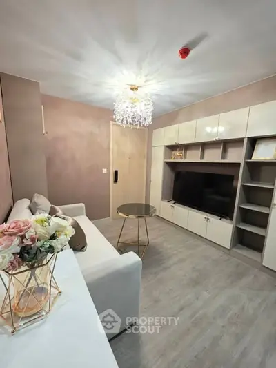 Elegant living room with modern decor, featuring a plush sofa, stylish chandelier, and built-in entertainment unit.