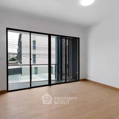 Spacious empty room with large windows and wooden flooring, perfect for customization.