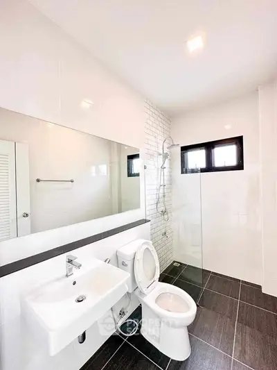 Modern bathroom with sleek fixtures and large mirror in a bright setting.