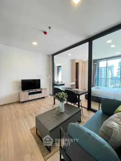 Modern open-plan living room with stylish furniture and large windows offering city views.