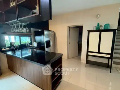 Modern kitchen with sleek black countertops and stainless steel appliances in a stylish home.