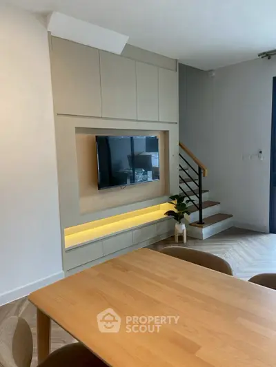 Modern living room with built-in TV and stylish staircase