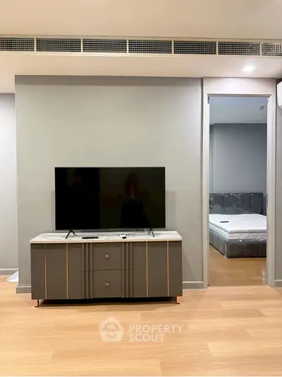 Modern living room with sleek TV stand and view into a stylish bedroom