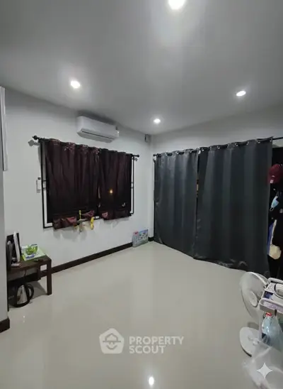 Spacious room with modern lighting and sleek curtains, perfect for versatile living arrangements.