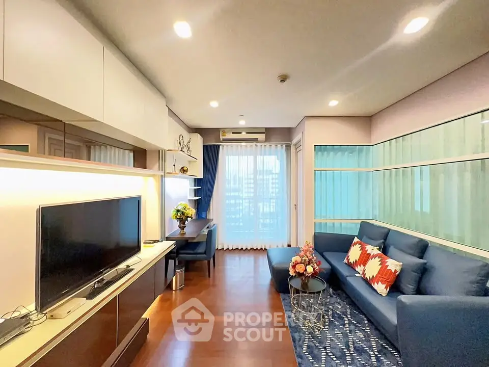 Modern living room with blue sofa, TV, and balcony view in stylish apartment.