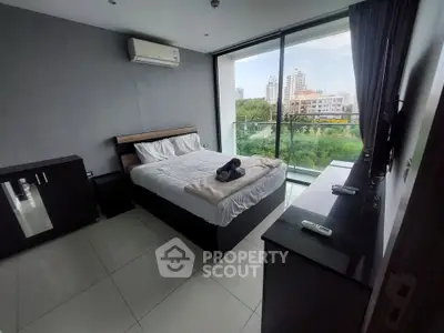 Modern bedroom with balcony and city view, featuring sleek furniture and air conditioning.