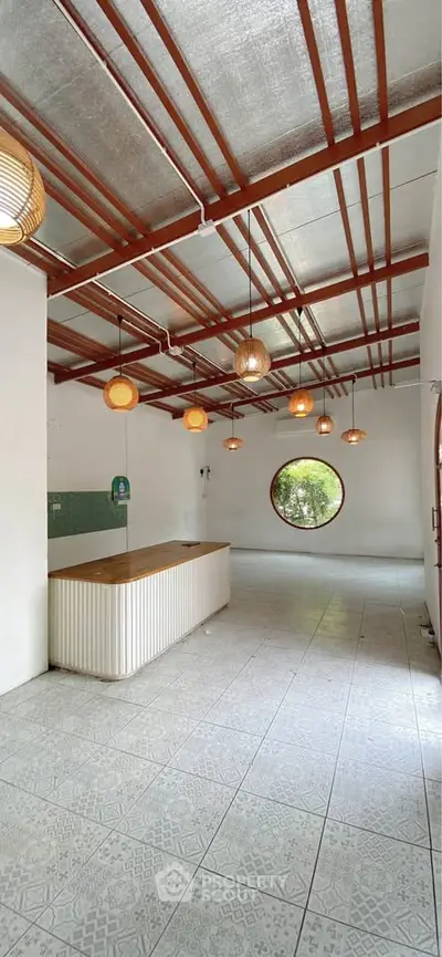 Spacious modern interior with unique round window and stylish lighting, perfect for creative living or workspace.