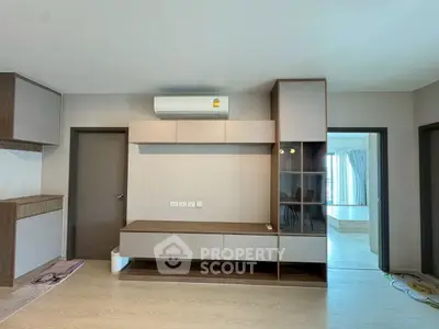 Modern living room with sleek built-in storage and air conditioning, featuring a glimpse into a bright bedroom.