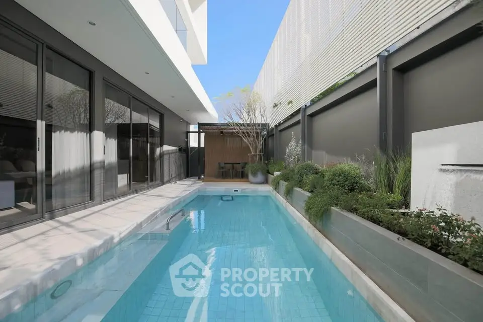 Luxurious modern home with sleek pool and stylish outdoor seating area, perfect for relaxation and entertainment.