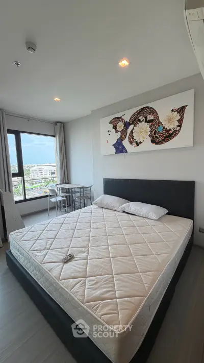 Spacious bedroom with modern decor and city view, featuring a large bed and stylish artwork.