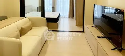 Modern living room with sleek TV and cozy sofa, open view to bedroom