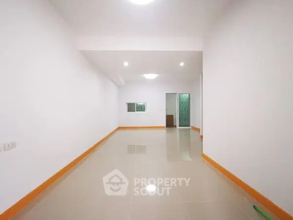 Spacious unfurnished room with glossy tiled floor and bright lighting