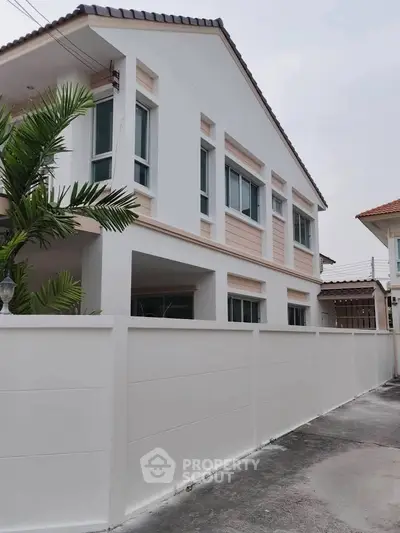 Modern two-story house with white facade and palm tree landscaping