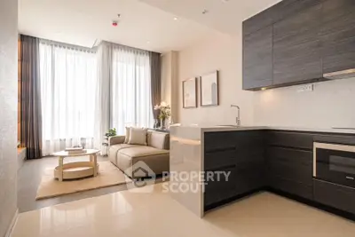 Modern open-layout living room with sleek kitchen, elegant decor, and ample natural light.