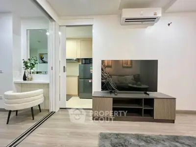 Modern living room with sleek TV unit and air conditioning, adjacent to a compact kitchen.