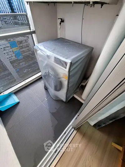 Compact balcony with washing machine and city view, ideal for urban living convenience.