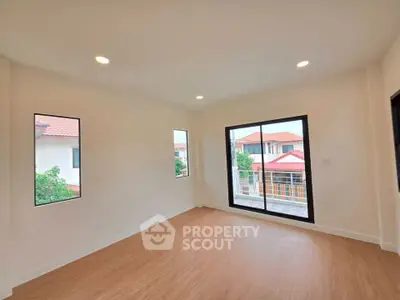 Spacious empty room with large windows and wooden flooring, offering a bright and airy atmosphere.
