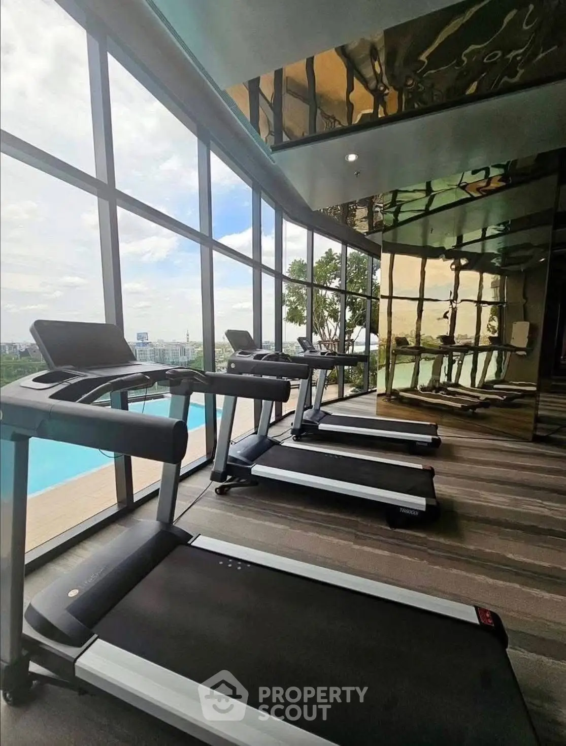 Luxurious gym with modern treadmills and pool view in upscale residential building.