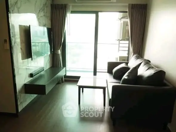 Modern living room with sleek furniture and large window offering natural light.