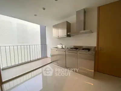 Modern kitchen with sleek stainless steel appliances and open layout, featuring a balcony view.