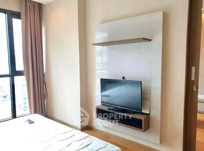 Modern bedroom with mounted TV and large window offering natural light.