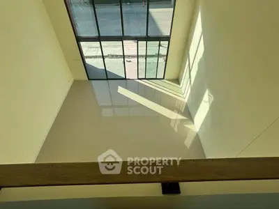 Spacious double-height living area with large windows and abundant natural light.