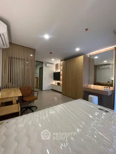 Modern bedroom with stylish wooden accents and workspace in a contemporary apartment.