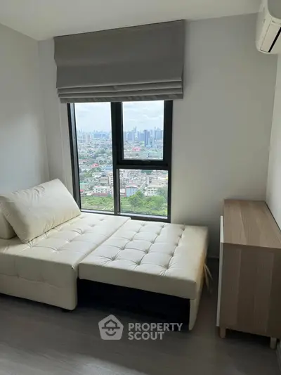 Modern bedroom with city view, featuring a stylish daybed and sleek storage unit.