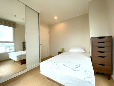 Bright and airy bedroom with large window offering city views, mirrored wardrobe doors, and sleek wooden furniture, perfect for urban living.