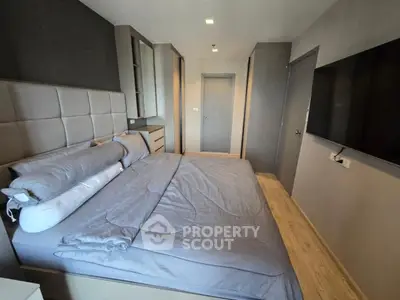 Modern bedroom with sleek design and large TV, featuring stylish headboard and cozy bedding.