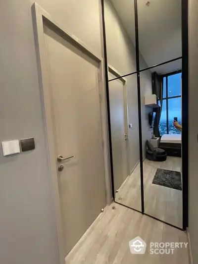 Modern apartment hallway with mirrored closet and view into stylish bedroom