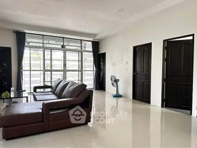 Spacious living room with modern leather sofa and large windows for natural light.