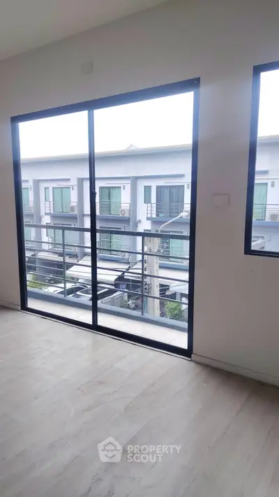 Spacious room with large windows offering a view of modern residential buildings.