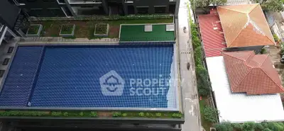 Aerial view of a modern apartment complex with a large swimming pool and landscaped surroundings.