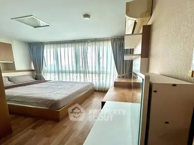 Cozy bedroom with large window and modern furnishings, perfect for relaxation.