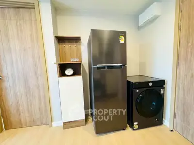 Modern kitchen with sleek fridge and washing machine in stylish apartment.
