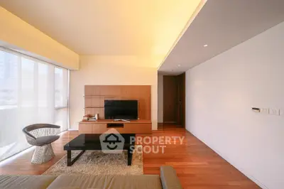 Spacious modern living room with wooden flooring and large windows for natural light.