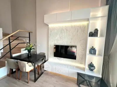 Modern living room with stylish decor and elegant staircase, featuring built-in TV unit and dining area.