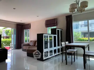 Spacious living room with modern furniture and large windows offering garden views.