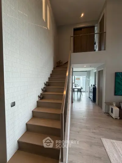 Modern duplex interior with stylish staircase and open living area, showcasing contemporary design and natural light.