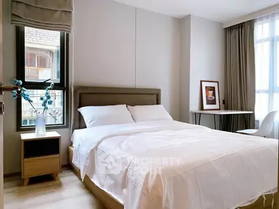 Modern bedroom with cozy bed, stylish decor, and ample natural light from large windows.
