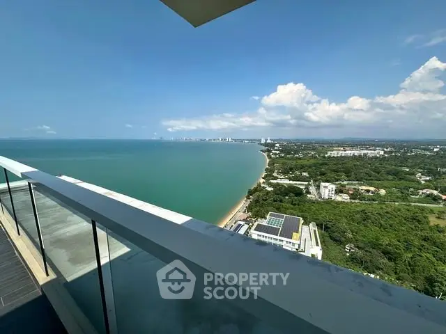 Stunning ocean view from high-rise balcony overlooking coastline and lush greenery.