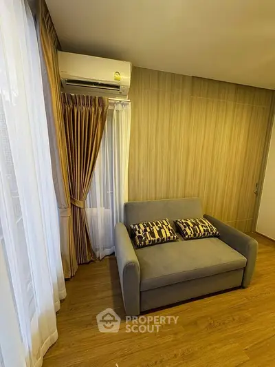 Cozy living room with modern sofa and air conditioning, featuring elegant curtains and wooden flooring.