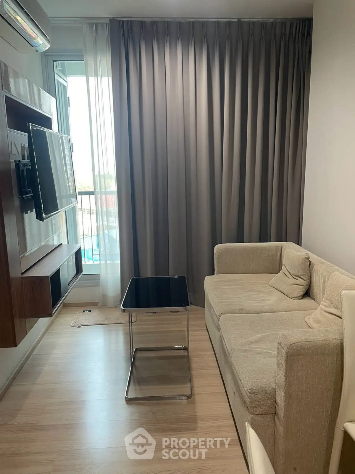 Modern living room with cozy sofa and wall-mounted TV, featuring a sleek design and natural light.