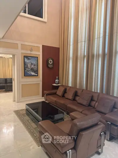 Luxurious living room with high ceilings, elegant decor, and plush leather seating in a sophisticated home.