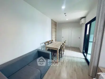 Modern living room with wooden dining set and cozy gray sofa, featuring sleek flooring and bright lighting.