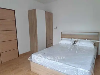 Modern minimalist bedroom with wooden furniture and a cozy bed setup.