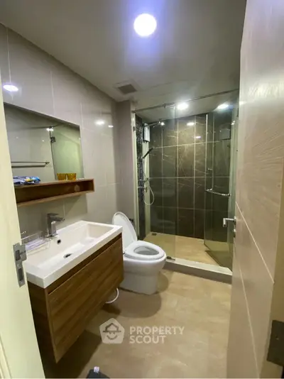 Modern bathroom with glass shower and sleek wooden vanity