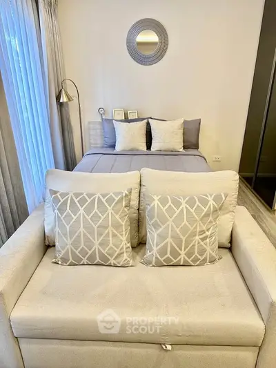 Cozy bedroom with elegant decor and neutral tones, featuring a plush bed and stylish sofa.