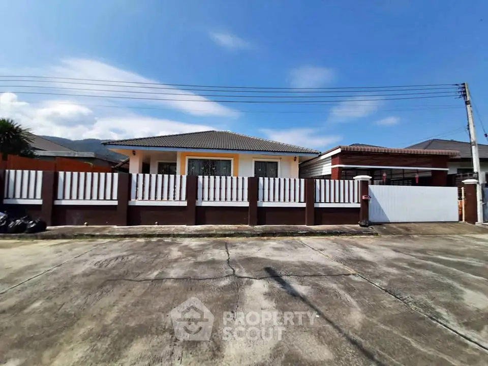 Charming single-story home with fenced yard and spacious driveway under clear blue skies.